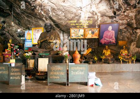 Thaïlande : Wat Tham Seua, ville de Krabi, province de Krabi, Sud de la Thaïlande. Wat Tham Seua, le « Temple de la grotte du tigre » est construit dans une grotte située dans une falaise calcaire. Entouré de résidences individuelles de moines, c'est l'un des temples forestiers les plus connus du sud de la Thaïlande. Le viharn principal ou salle de rassemblement se prolonge dans une longue grotte calcaire peu profonde affichant divers sombres rappels de la mortalité comme contrepoids aux désirs mondains. À l'arrière de la grotte, un escalier en marbre mène à la « grotte du tigre » elle-même. À l'intérieur, il y a une empreinte vénérée de Bouddha sur une plate-forme dorée. Banque D'Images