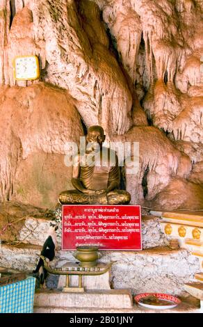 Thaïlande : statue d'abbé, Wat Tham Seua, ville de Krabi, province de Krabi, Sud de la Thaïlande. Wat Tham Seua, le « Temple de la grotte du tigre » est construit dans une grotte située dans une falaise calcaire. Entouré de résidences individuelles de moines, c'est l'un des temples forestiers les plus connus du sud de la Thaïlande. Le viharn principal ou salle de rassemblement se prolonge dans une longue grotte calcaire peu profonde affichant divers sombres rappels de la mortalité comme contrepoids aux désirs mondains. À l'arrière de la grotte, un escalier en marbre mène à la « grotte du tigre » elle-même. Banque D'Images