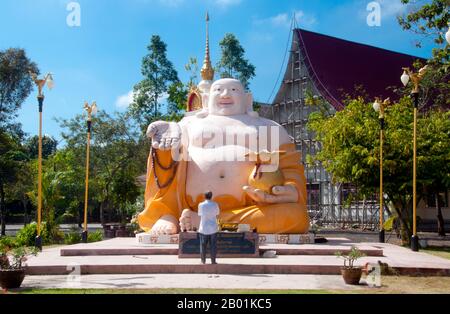 Thaïlande : la statue de Phra Sangkajjayana (Bouddha riant ou Budai), Wat Matchimaphum, ville de Trang, province de Trang, sud de la Thaïlande. Budai, prononcé Hotei en japonais et Bố Đại en vietnamien, est une divinité folklorique chinoise. Son nom signifie «sac en tissu» et vient du sac qu'il est classiquement représenté comme portant. Il est généralement identifié avec (ou comme une incarnation de) Bouddha Maitreya, à tel point que l'image Budai est l'une des principales formes dans lesquelles le Bouddha Maitreya est représenté en Asie de l'est. Il est presque toujours montré souriant ou riant, d'où son surnom chinois, le Bouddha riant Banque D'Images