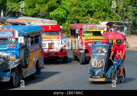 Philippines : jeepneys et pédicab, Anda Circle, Bonifacio Drive, près d'Intramuros, Manille. Les jeepneys sont le moyen de transport public le plus populaire aux Philippines. Ils ont été fabriqués à l'origine à partir de jeeps militaires américaines laissées de la Seconde Guerre mondiale et sont connus pour leur décoration flamboyante et leurs sièges bondés. Ils sont devenus un symbole omniprésent de la culture philippine. Banque D'Images