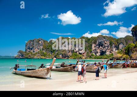 Thaïlande : bateaux d'excursion alignés sur la plage, Hat Rai Leh Ouest, côte de Krabi. Hat Rai Leh se divise en deux plages, est et Ouest. Le premier, Rai Leh East, est plutôt boueux à marée basse, et les gens séjournant ici ont tendance à fréquenter Rai Leh West. Hat Rai Leh West est plus sain et généralement plus attrayant. La province de Krabi est composée de plus de 5 000 km2 de collines couvertes de jungle et d'affleurements karstiques pointus et déchiquetés, ainsi que de plus de 100 km de côtes luxuriantes et immaculées et d'environ 200 îles dans la mer d'Andaman voisine. Banque D'Images