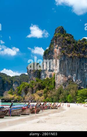 Thaïlande : bateaux d'excursion alignés sur la plage, Hat Rai Leh Ouest, côte de Krabi. Hat Rai Leh se divise en deux plages, est et Ouest. Le premier, Rai Leh East, est plutôt boueux à marée basse, et les gens séjournant ici ont tendance à fréquenter Rai Leh West. Hat Rai Leh West est plus sain et généralement plus attrayant. La province de Krabi est composée de plus de 5 000 km2 de collines couvertes de jungle et d'affleurements karstiques pointus et déchiquetés, ainsi que de plus de 100 km de côtes luxuriantes et immaculées et d'environ 200 îles dans la mer d'Andaman voisine. Banque D'Images