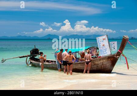 Thaïlande : les visiteurs achètent des collations à l'un des bateaux de restauration alignés sur la plage de Hat Tham Phra Nang, Krabi Coast Hat Tham Phra Nang, la «plage de la dame vénérée», est une belle plage de sable blanc à l'extrémité sud de la petite péninsule séparant Rai le East Beach de Rai Leh West Beach. La plage est considérée par beaucoup comme la plus belle de la région de Krabi, et aussi l'une des plus belles du sud de la Thaïlande. Composé de sable blanc et croquant et abrité par de hautes falaises de calcaire, le cadre idéal est rehaussé par des affleurements karstiques pointus et aux formes étranges. Banque D'Images