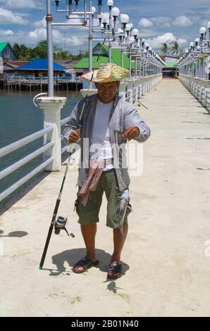 Thaïlande : pêcheur à la jetée Ban Laem Kruat, point de ferry pour les îles de Ko si Boya et Ko Jam, côte de Krabi. La province de Krabi est composée de plus de 5 000 km2 de collines couvertes de jungle et d'affleurements karstiques pointus et déchiquetés, ainsi que de plus de 100 km de côtes luxuriantes et immaculées et d'environ 200 îles dans la mer d'Andaman voisine. Environ 40 % de la population provinciale est musulmane, le reste étant majoritairement bouddhiste. Ceci est une indication claire que Krabi se trouve à cheval sur la ligne de démarcation invisible entre la Thaïlande bouddhiste et les quatre provinces du sud. Banque D'Images