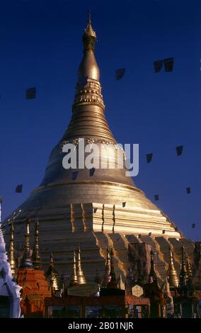 Birmanie/Myanmar : pagode Shwedagon, Yangon (Rangoon). Le stupa doré de la pagode Shwedagon s'élève à près de 100 m (330 pi) au-dessus de son cadre sur la colline Singuttara et est plaqué de 8 688 dalles en or massif. Ce stupa central est entouré de plus de 100 autres bâtiments, y compris des stupas et des pavillons plus petits. La pagode était déjà bien établie lorsque Bagan dominait la Birmanie au 11e siècle. La reine Shinsawbu, qui régna au 15e siècle, aurait donné à la pagode sa forme actuelle. Elle a également construit les terrasses et les murs autour du stupa. Banque D'Images