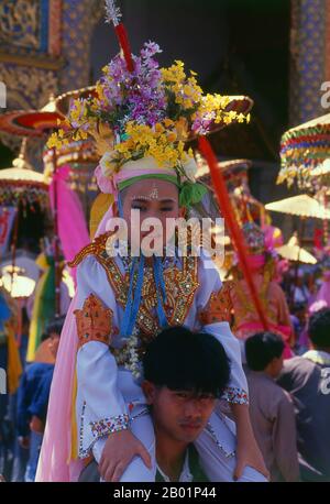 Thaïlande : un 'fils de cristal' est assis sur les épaules d'un parent et attend sa dernière ordination au Wat Phra Singh, Poy sang long Festival, Chiang Mai, nord de la Thaïlande. Une fois par an, Wat Pa Pao accueille les luk kaeo, ou « fils de cristal » - de jeunes garçons Shan sur le point d'être ordonnés dans le monkhood bouddhiste. Beaucoup de ces novices se rendent à Chiang Mai depuis les communautés Shan environnantes de Mae Cham, Mae Rim, Chiang Dao et Fang. Cette cérémonie Shan annuelle est appelée Poy sang long. Pendant le jour de la cérémonie, les «fils de cristal» et leurs proches passent de Wat Pa Pao à Wat Phra Singh. Banque D'Images