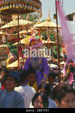 Thaïlande : un 'fils de cristal' est assis sur les épaules d'un parent et attend sa dernière ordination au Wat Phra Singh, Poy sang long Festival, Chiang Mai, dans le nord de la Thaïlande. Une fois par an, Wat Pa Pao accueille les luk kaeo, ou « fils de cristal » - de jeunes garçons Shan sur le point d'être ordonnés dans le monkhood bouddhiste. Beaucoup de ces novices se rendent à Chiang Mai depuis les communautés Shan environnantes de Mae Cham, Mae Rim, Chiang Dao et Fang. Cette cérémonie Shan annuelle est appelée Poy sang long. Pendant le jour de la cérémonie, les «fils de cristal» et leurs proches passent de Wat Pa Pao à Wat Phra Singh. Banque D'Images