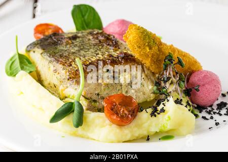 Un morceau de saumon cuit au four au poivre grillé au citron et au sel sur une plaque brune avec feuilles de laitue. Fond de bois Banque D'Images