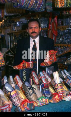 Syrie : propriétaire d'un magasin de chaussures dans le souk artisanal restauré dans le Grand Bazar d'Alep. Le Grand Bazar d'Alep (en arabe, suq ou souq) tel que nous le connaissons aujourd'hui a été reconstruit d'abord par les Mamelouks égyptiens qui ont chassé les Mongols, puis, après 1516, par les Turcs qui ont incorporé Alep dans l'Empire ottoman. Alep, la deuxième ville de Syrie et très probablement la plus longue colonie continuellement habitée dans le monde, est d'un âge vénérable. Si vieux, en effet, que son nom arabe, Halab, est mentionné pour la première fois dans les textes sémitiques du troisième millénaire avant notre ère. Banque D'Images