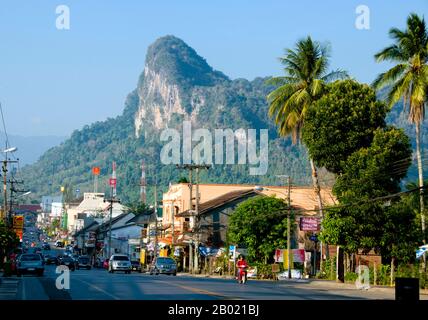 Thaïlande : des pics calcaires surplombent la rue principale de Phangnga Town. Phang Nga Town, la capitale de la province de Phang Nga, est une ville plutôt délabrée dans un endroit spectaculaire qui semble destiné à être toujours éclipsé par l'essor, voisin de Phuket. Il y a beaucoup à faire et à voir dans les environs, en particulier dans la belle baie de Phang Nga, mais très peu de visiteurs choisiront de rester en ville étant donné l'alléchant - et franchement beaucoup plus confortable - hébergement disponible dans les stations balnéaires voisines de l'île de Phuket. Banque D'Images