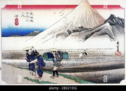 Japon : 'Station treize : Mont Fuji le matin, Hara'. Estampe sur bois ukiyo-e de la série 'cinquante-trois stations de la route de Tôkaidô' par Utagawa Hiroshige (1797-1858), vers 1833-1834. Hara : deux femmes wayfarers, et un coolie portant leurs boîtes, passant le long des rizières, dominé par l'énorme masse enneigée de Fuji. Le quartier de Hara est considéré comme le meilleur point de vue pour une vue magnifique sur le mont Fuji. À l'époque d'Edo, les déplacements sur l'autoroute étaient considérés comme très dangereux et les femmes voyageant étaient généralement accompagnées de leur servante. Banque D'Images