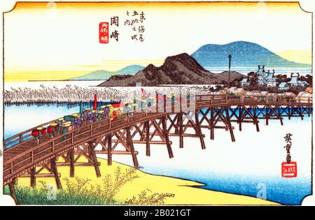 Japon : 'Station trente-huit : pont Yahagi à Okazaki'. Estampe sur bois ukiyo-e de la série 'cinquante-trois stations de la route de Tôkaidô' par Utagawa Hiroshige (1797-1858), vers 1834. Okazaki : cortège d'un daimyo traversant le pont sur la rivière Yahagi vers le village et le château sur la rive suivante ; en arrière-plan une colline bleue, imprimée à partir de blocs de couleurs seulement. Tokugawa Ieyasu, le fondateur du shogunat Tokugawa, est né dans le château montré dans les estampes. Le pont sur la rivière Yahagi, coulant à l'ouest du château, était le plus grand de toute la route. Banque D'Images