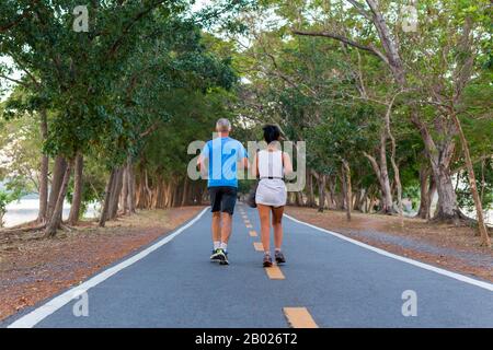 Vue arrière des couples seniors en jogging dans le parc public. Banque D'Images
