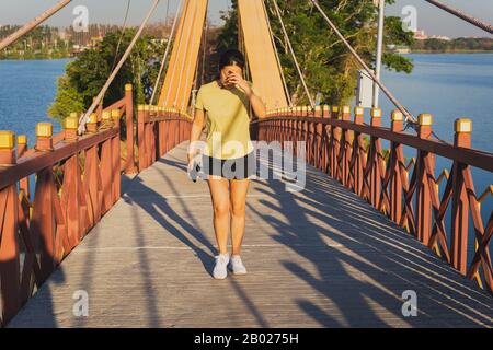 Femme faire de l'exercice en marchant sur un pont le jour ensoleillé de l'été. Banque D'Images