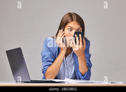 Une femme en colère dans un t-shirt blanc hurlant au téléphone, regardant à l'écran, ennuie femme lire de mauvaises nouvelles, problème avec téléphone portable cassé ou déchargé, Banque D'Images