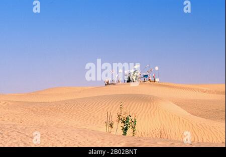 Chine : un tombeau avec des drapeaux un flottant plane sur les dunes de sable près de l'Imam Asim Mazar (sanctuaire) dans le désert près de Khotan, province du Xinjiang. Le sanctuaire de l'Imam Asim et d'autres tombes se trouvent à 23 kilomètres de Khotan (Hotan) sur la route de la soie au sud. C'est le site d'un immense pèlerinage chaque mois de mai. L’Imam Asim a été l’un des premiers missionnaires islamiques à visiter cette région. Khotan retrace son histoire au moins aussi loin que le IIIe siècle av. J.-C., lorsque le fils aîné de l'empereur indien Asoka s'est installé ici. Banque D'Images