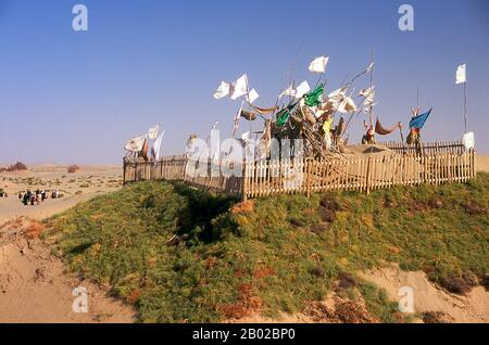Chine : les pèlerins approchent d'une tombe dans les dunes de sable près de l'Imam Asim Mazar (sanctuaire) dans le désert près de Khotan, province du Xinjiang. Le sanctuaire de l'Imam Asim et d'autres tombes se trouvent à 23 kilomètres de Khotan (Hotan) sur la route de la soie au sud. C'est le site d'un immense pèlerinage chaque mois de mai. L’Imam Asim a été l’un des premiers missionnaires islamiques à visiter cette région. Khotan retrace son histoire au moins aussi loin que le IIIe siècle av. J.-C., lorsque le fils aîné de l'empereur indien Asoka s'est installé ici. Banque D'Images