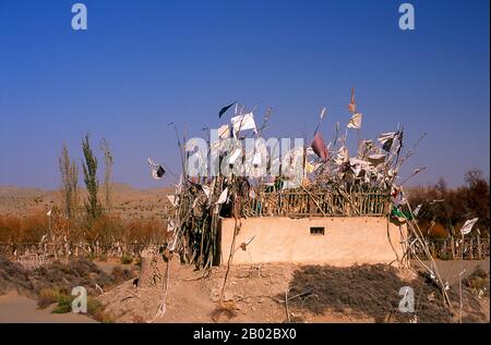 Chine : un tombeau dans les dunes de sable près de l'Imam Asim Mazar (sanctuaire) dans le désert près de Khotan, province du Xinjiang. Le sanctuaire de l'Imam Asim et d'autres tombes se trouvent à 23 kilomètres de Khotan (Hotan) sur la route de la soie au sud. C'est le site d'un immense pèlerinage chaque mois de mai. L’Imam Asim a été l’un des premiers missionnaires islamiques à visiter cette région. Khotan retrace son histoire au moins aussi loin que le IIIe siècle av. J.-C., lorsque le fils aîné de l'empereur indien Asoka s'est installé ici. C'était d'une grande importance sur la route de la soie. Banque D'Images