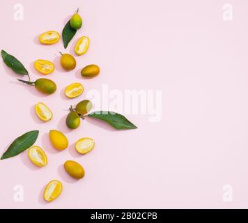 Fruits kumquat coupés en deux, sur fond rose, orientation horizontale. Espace de copie Banque D'Images