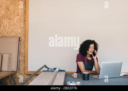 Jeune femme parlant au téléphone dans son studio de cadrage Banque D'Images