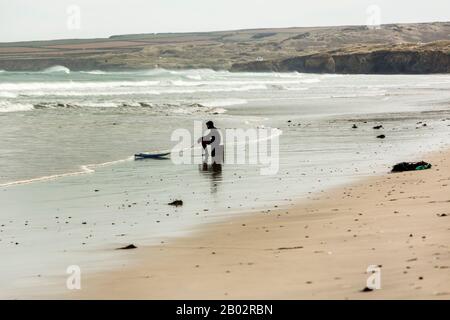 Un surfeur déjecté ou fatigué est assis sur une boîte avec son surf, Portreath, Cornwall, Angleterre Banque D'Images