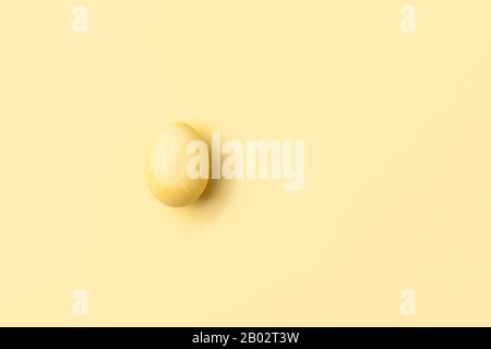 Un œuf jaune pastel minimum. Bonne conception de carte de vœux monochrome joyeuse de Pâques. Plat, vue de dessus, espace de copie pour le texte, orientation horizontale Banque D'Images