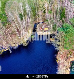 Vue aérienne depuis le sommet d'un lac bleu foncé de lune dans la bruyère avec une petite cabane sur la rive Banque D'Images