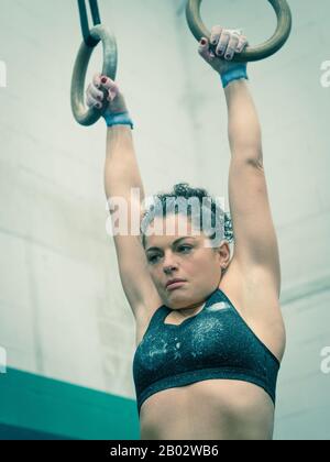 L'athlète de femme pend des anneaux dans la gymnastique Banque D'Images