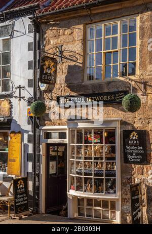 Un vieux bâtiment abrite une boutique pittoresque vendant Whitby jet. Un soleil bas éclaire la pierre et les ombres tombent dessus. Banque D'Images