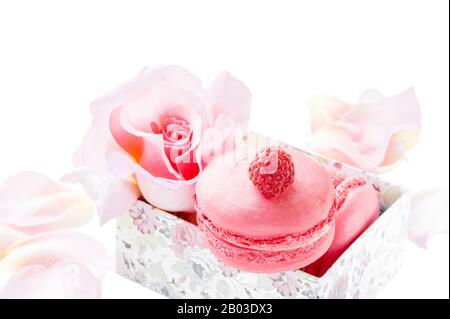 Macarons roses framboises et fraises sur le décor du lit Valentine et fleurs roses isolent Les Macarons Délicats sur la table sur un fond blanc. Banque D'Images