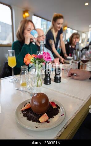 Serveuse servant nourriture, dessert et café, Darcie et May Green flottant restaurant, Grand Union Canal, Paddington Londres UK Banque D'Images