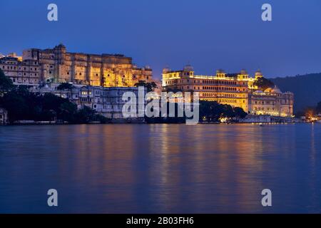 La nuit a tourné au-dessus du lac Pichola sur le palais illuminé de la ville et le palais Taj Fateh Prakash d'Udaipur, Rajasthan, Inde Banque D'Images