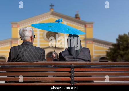 Couple de personnes âgées assis sur le banc et tenant un parapluie à Shkoder, en Albanie Banque D'Images