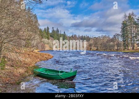 VILLAGE DE CARRON MORAY ECOSSE VUE SUR UN BATEAU DE PÊCHE VERT ET LA RIVIÈRE DEPUIS LA ROUTE UNIQUE DE CARRON ET LE VIEUX PONT FERROVIAIRE QUI TRAVERSE LA RIVIÈRE SPEY Banque D'Images