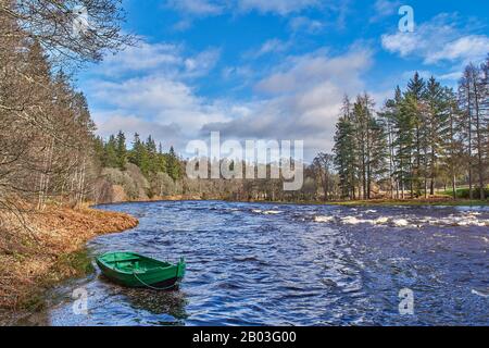 VILLAGE DE CARRON MORAY ECOSSE VUE SUR LE BATEAU DE PÊCHE VERT ET LA RIVIÈRE DEPUIS LA ROUTE UNIQUE DE CARRON ET LE VIEUX PONT FERROVIAIRE QUI TRAVERSE LA RIVIÈRE SPEY Banque D'Images