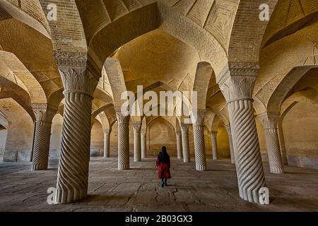 Mosquée Vakil avec une Iranienne en robe rouge sous ses arches, à Shiraz, Iran Banque D'Images