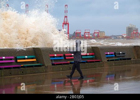 Un homme se rapproche dangereusement du mur de la mer pour prendre une photo avant qu'une énorme vague ne s'arrête à New Brighton pendant la tempête Ciara. Banque D'Images