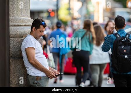 New York, États-Unis - 21 juin 2019: L'homme se tient sur le côté de la rue et regarde le smatrfon Banque D'Images