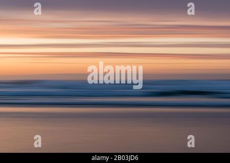 Mouvement intentionnel de caméra utilisé pour créer un effet de superposition flou pendant un coucher de soleil à Godrevy Beach, Cornwall Banque D'Images