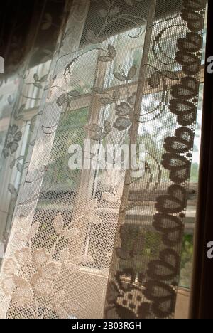 À travers un rideau de dentelle donnant sur la rue ci-dessous. Banque D'Images