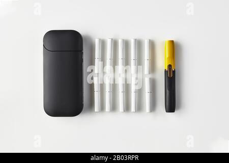 La cigarette électronique noire de nouvelle génération se trouve sur des  paquets de côtés rouge et jaune, sur batterie, isolée sur blanc. Nouvelle  technologie. Chauffage du système de tabac. T Photo Stock -