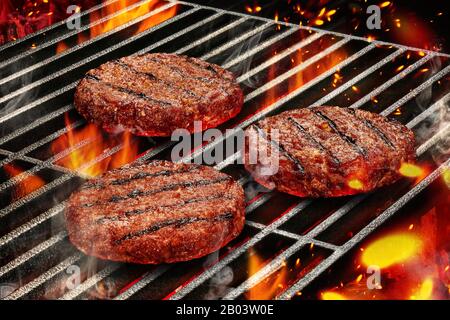 Cuisson au gril de la préparation des côtelettes de porc pour les hamburgers. Viande rôtie sur un barbecue d'été portable en métal avec feu flammant brillant et feu de barre Banque D'Images