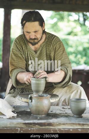 Potier traditionnel utilisant l'ancienne méthode dacienne sur une roue d'argile à pied au Musée du Village à Baia Mare, Maramureș, Roumanie Banque D'Images