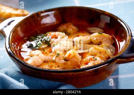 Queues de scampi méditerranéens fraîches et épicées gastronomiques garnies d'herbes et servies dans un bol en faïence brune en gros plan Banque D'Images