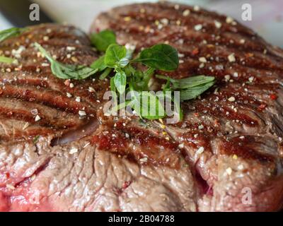 Un gros morceau de bœuf frais juteux parsemé d'épices et d'herbes. Rayures rares, le jus de la viande. Gros plan, vue de face Banque D'Images