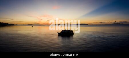 Silhouettes de lever de soleil une plongée à bord d'un bateau à Raja Ampat, Indonésie. Cette région est considérée comme le centre de la biodiversité marine. Banque D'Images