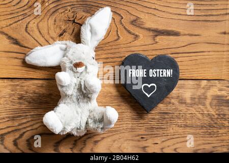 Lapin farci avec message 'Hapy Easter' en allemand sur fond de bois Banque D'Images