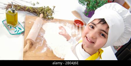 vue de dessus d'un enfant chef souriant vêtu d'un ensemble chaleureux Banque D'Images