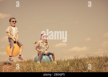 Frère et sœur jouant sur le terrain à la journée. Les enfants s'amuser en plein air. Ils sauter sur des ballons gonflables sur la pelouse. Concept d'ami Banque D'Images