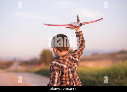 Petit garçon avec un avion jouet jouant au printemps extérieur image
